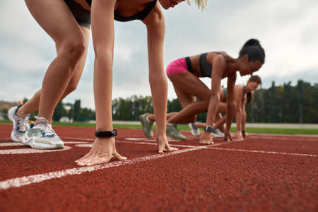 Closeup of arms with smart watch of professional female runner ready to start race on track field at stadiumの写真素材