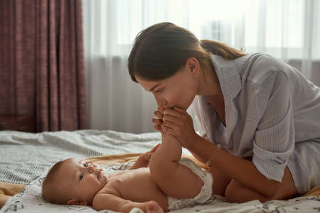 mother kissing with tenderness newborn baby feet
