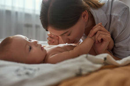 Sweet moment when mother gently kissing babys bellyの写真素材