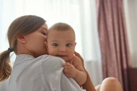 Cheerful baby in mothers embrace. Family moments