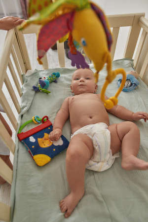 Cute baby without clothes, peacefully lying in bedの写真素材