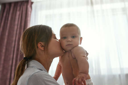 Portrait of a mother with her baby in bedroom at home