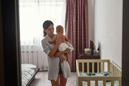 Young troubled mother trying to comfort her babyの写真素材