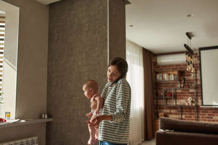 Young worried mother calling doctor on mobile phoneの写真素材