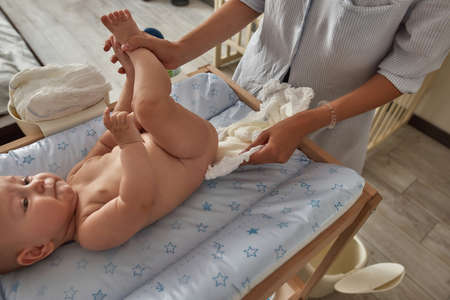 Mother putting on fresh diaper under babyの写真素材