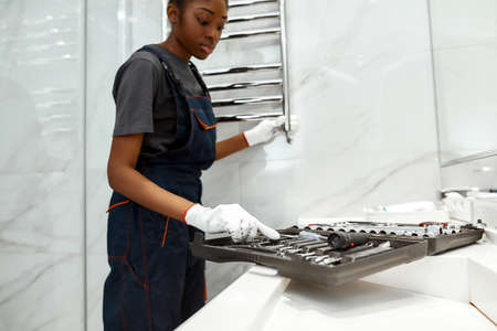 Female plumber choosing right combination wrench to fix towel rail