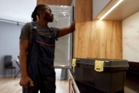 Service toolkit on kitchen surface, handyman on background, blured