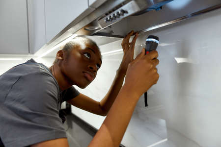 Attractive handywoman with torch troubleshooting kitchen exhaustの写真素材