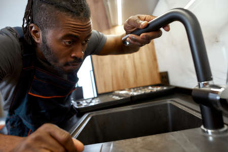 Closeup portrait African plumber holding kitchen tapの写真素材