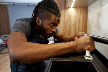 Professional plumber fixing water tap in kitchen, close viewの写真素材