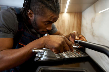 Skilled plumber fixing kitchen tap with spannerの写真素材