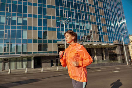 Sporty young woman in earphones run outdoorsの写真素材