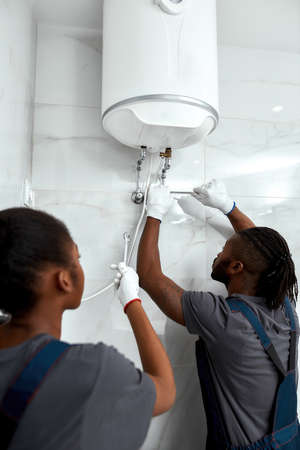 Repairman in white gloves installing electric boiler
