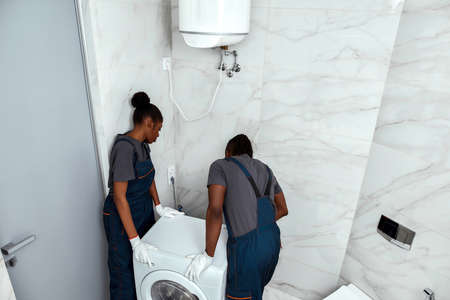 Moving company staff members replacing waching machine