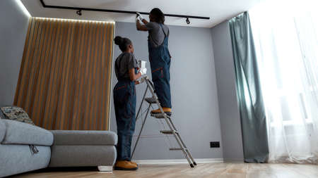 Man replacing light bulb with womans assistance