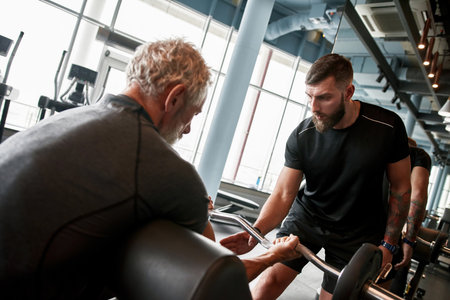 Fit senior man in gym, holding curved barbellの写真素材