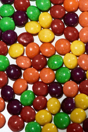 Top view of colorful chocolate coated candies on a white background