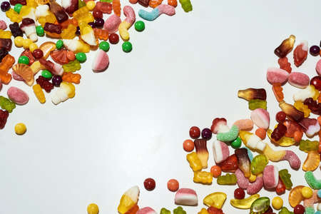Colorful jelly sweets made from fruit juice, gelatin and sugar in the corners isolated over white backgroundの写真素材