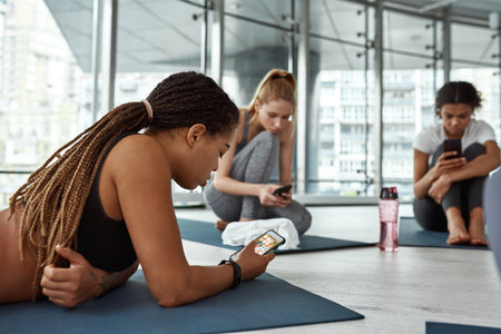 Young black woman use smartphone at workout in gymの写真素材