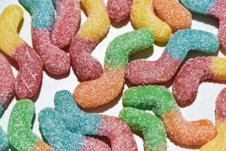 Close up shot of many tasty colorful sour sugar coated gummy worms isolated over white backgroundの写真素材