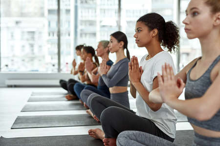 Active multiracial women practice yoga meditate on classの写真素材