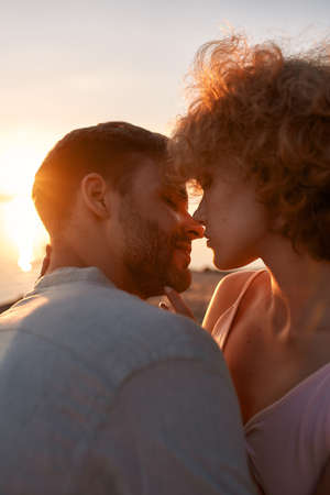 Young couple in love closing their eyes before kiss while spending time on the beach at sunsetの写真素材