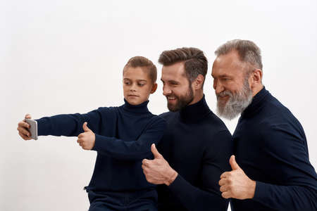 Smiling three generations of men make selfie on smartphoneの写真素材