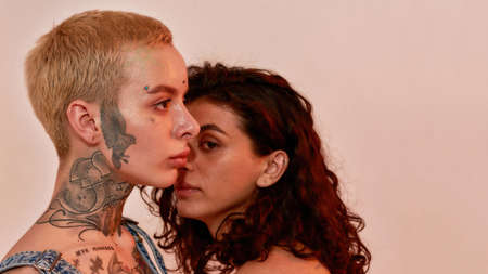 Closeup portrait of two young generation Z lesbian couple posing together isolated over light pink backgroundの写真素材
