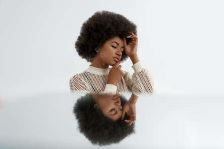 Thinking curly black woman with mirror reflectionの写真素材