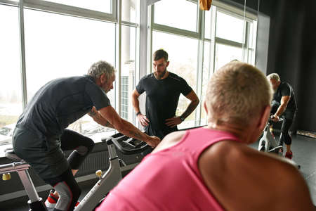 Two senior people on bikes in gym