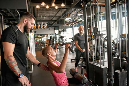 Woman training power lifting under professional trainers supervision