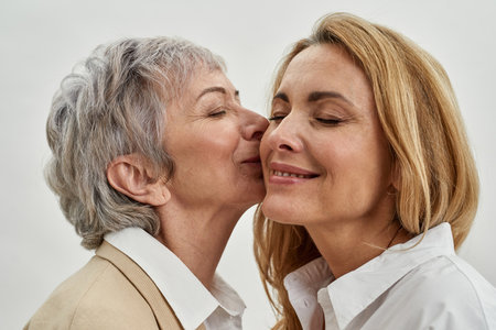 Older Caucasian mother kiss adult daughterの写真素材