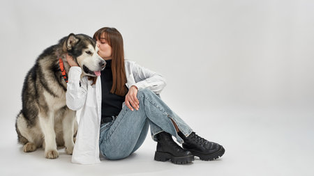 Woman caressing and kissing Siberian Husky dog