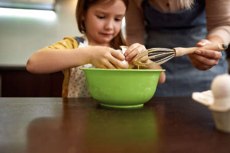 Caucasian little girl breaking egg with grandmaの写真素材