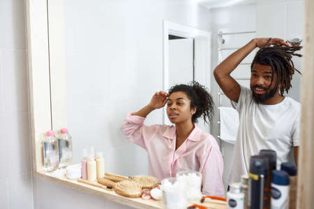 Mirror reflection of black couple looking at facesの写真素材