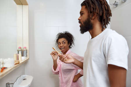 Side view of couple brushing teeth in bathroomの写真素材