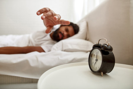 Man stopping alarm clock during sleeping on bed