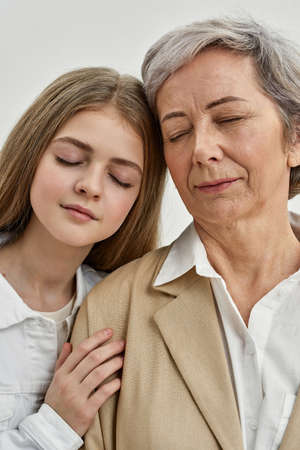 Teenage girl hugging senior woman in studioの写真素材