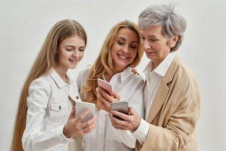 Smiling three females use and watch smartphonesの写真素材