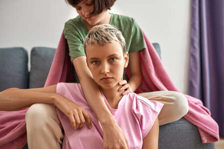 Cropped of girl on sofa hug serious girlfriend