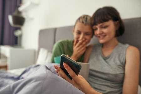 Selective focus of smartphone in hands of lesbiansの写真素材