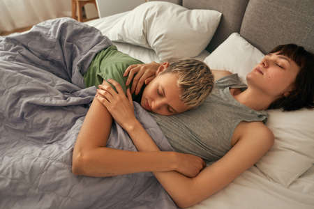 Attractive lesbian girls sleeping on bed at home
