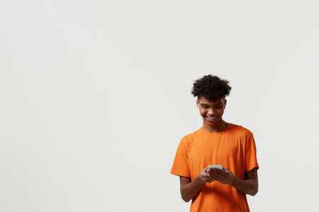 Smiling man in wireless earphones using smartphoneの写真素材