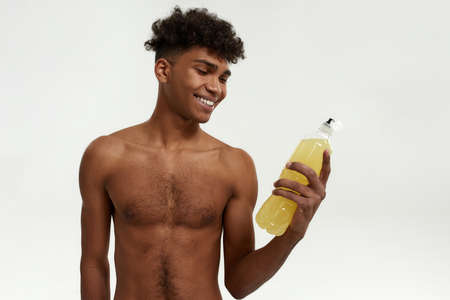 Smiling sportsman look on bottle with sport drinkの写真素材