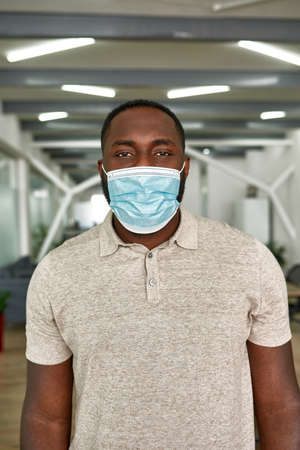 Young african man in medical mask look at camera
