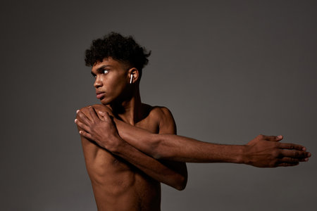 Black sports man in wireless earphones stretchingの写真素材