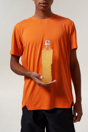 Cropped of black man holding yellow sport drinkの写真素材