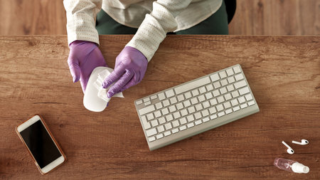 Cropped of girl wiping computer mouse at desk