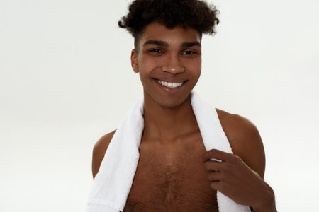 Smiling curly sportsman with towel look at cameraの写真素材