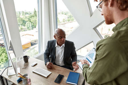 Man showing statistics to boss with skeptical faceの写真素材